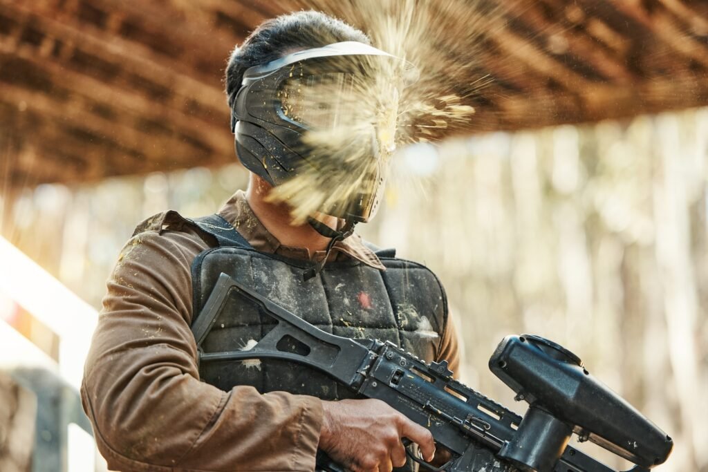 Paintball gun, man and splash on mask, shooting and target with attack, strategy and gear for safet