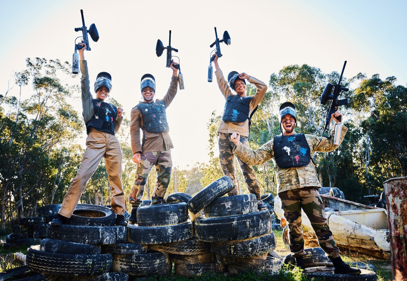 Team, paintball and portrait in celebration for winning, victory or achievement standing on tires t